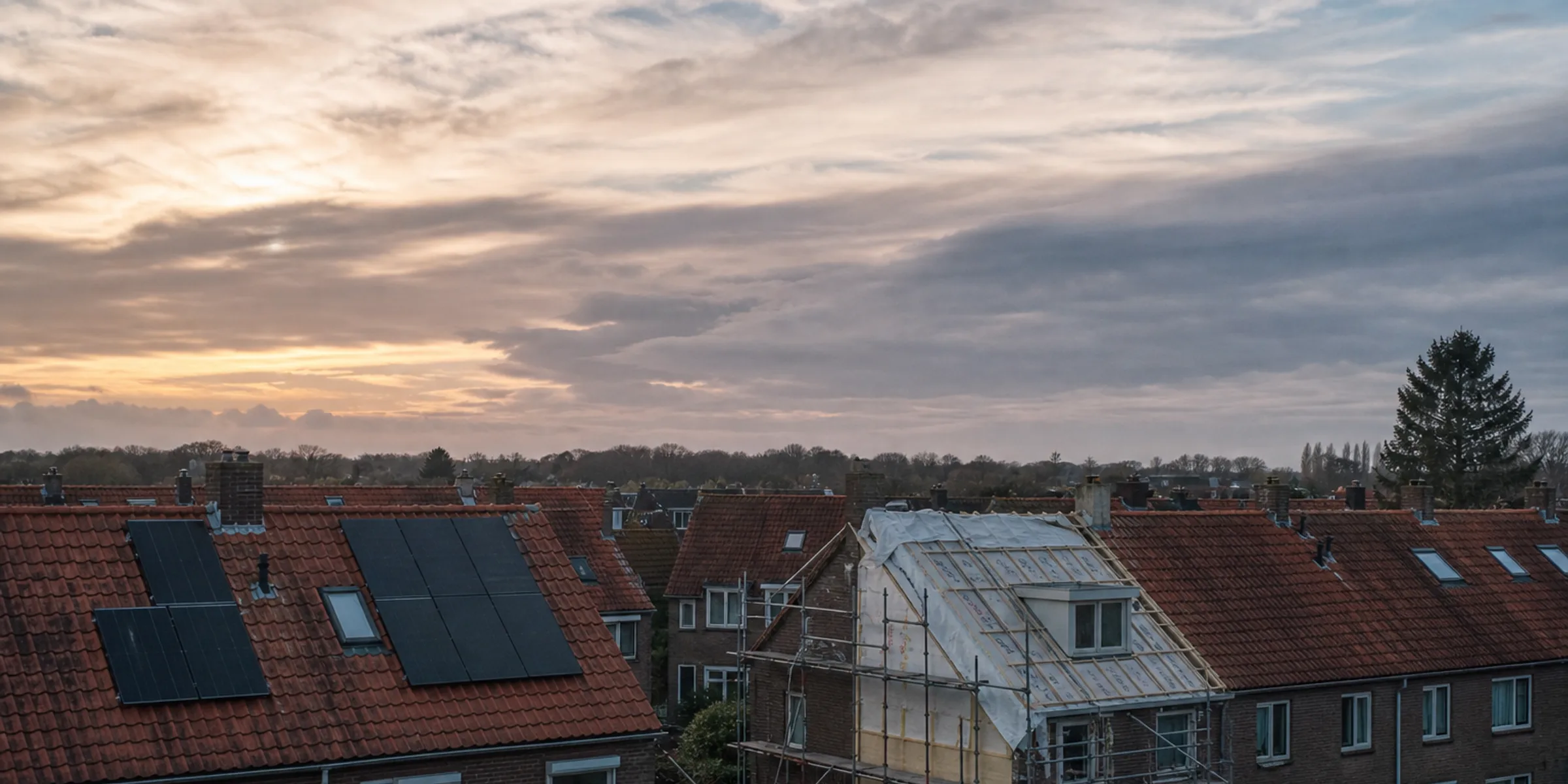 Nederlandse rijtjeshuizen met zonnepanelen en isolatiewerk in de steigers